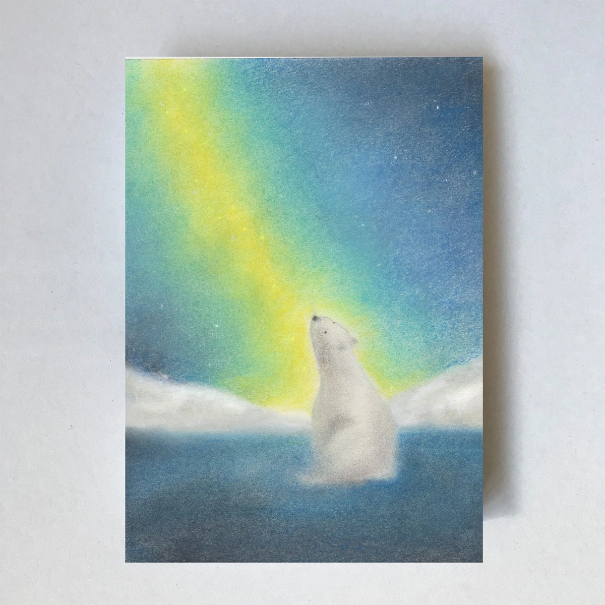 Postkarte Eisbär von Lot Bouwes A6: ein Eisbär sitzt auf dem Eis und schaut zum grün-gelben Nordlicht hinauf