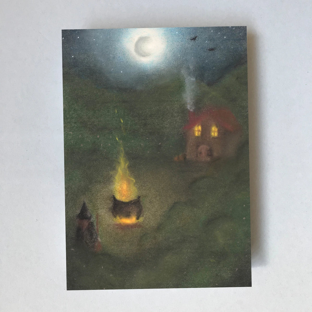 Postkarte Hexenhütte von Lot Bouwes A6: eine Hexe sitzt nachts am Feuer unter einem dampfenden Kessel, dahinter ihr Hexenhaus mit leuchtenden Fenstern, Mond, Fledermäuse