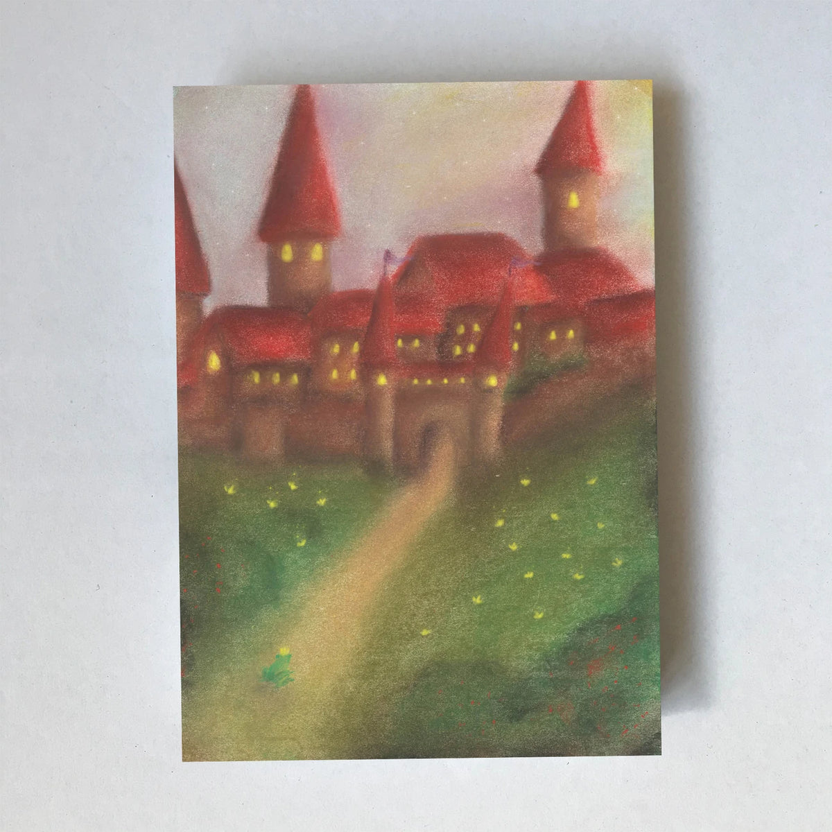 Postkarte Schloss und Froschkönig von Lot Bouwes A6: rotes Schloss mit spitzen Türmen und leuchtenden Fenstern, Weg über grüne Wiese, kleiner grüner Frosch auf dem Weg