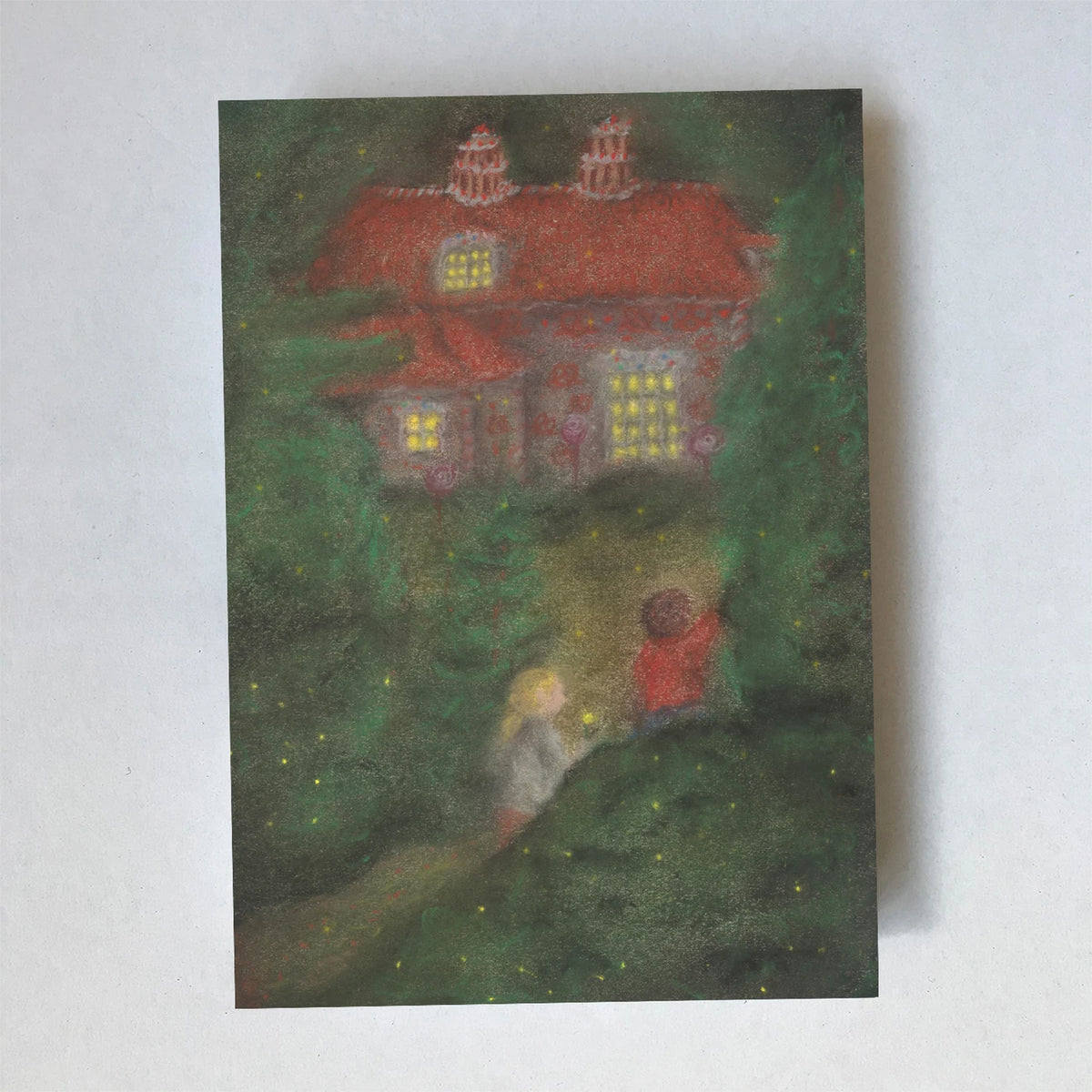 Postkarte Süßigkeitenhaus von Lot Bouwes A6: Hänsel und Gretel stehen im dunklen Wald vor dem Süßigkeitenhaus mit leuchtenden Fenstern