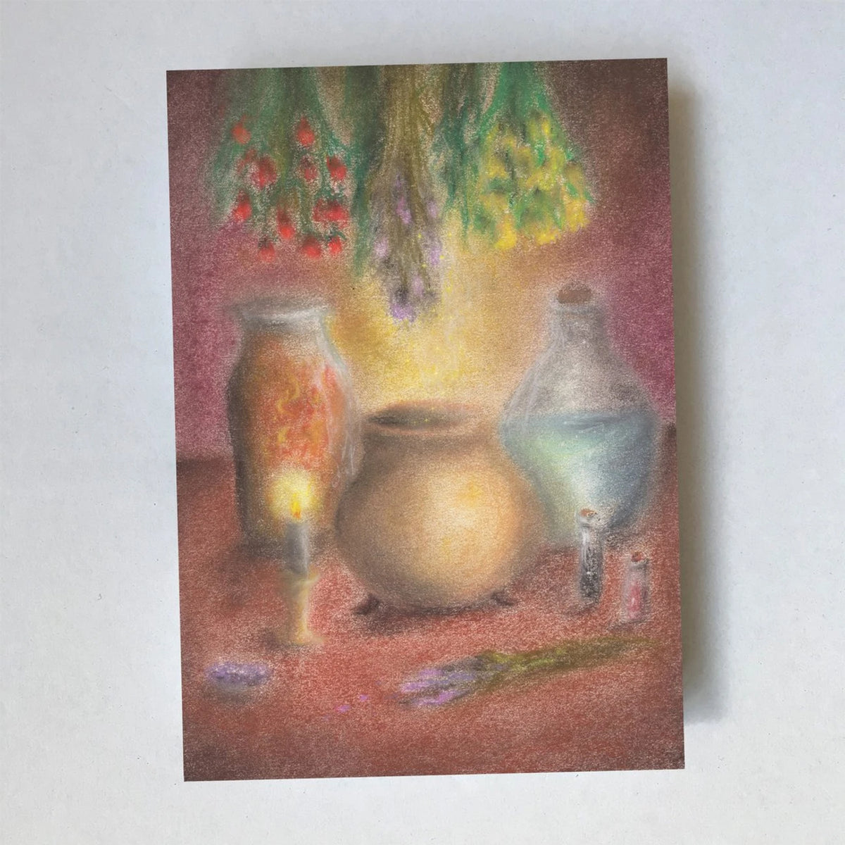 Postkarte Zaubertrank von Lot Bouwes A6: Zaubertrank-Werkstatt: Glasflaschen, ein großer Tonkessel, eine Kerze, getrocknete Kräuter hängen von der Decke