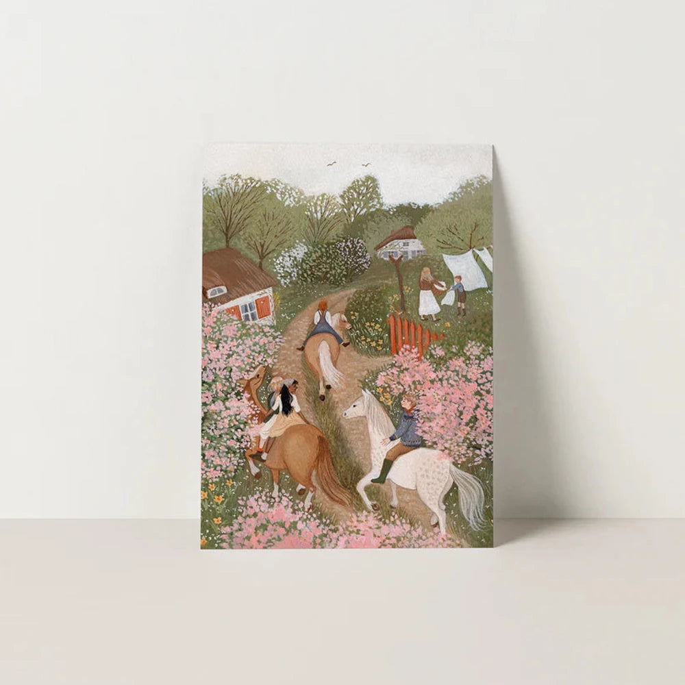 Postkarte Ausritt in der Blütezeit von Robin Pieterse A6: Kinder reiten auf Pferden einen Feldweg zwischen rosa blühenden Hecken entlang, im Hintergrund Häuser und Wäsche auf der Leine