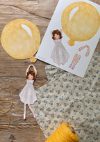 Bastelbogen Mobile Mädchen mit gelbem Ballon von Tall Hat Tales, Bogen und ausgeschnittenes Mädchen am gelben Ballon auf Holz