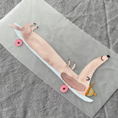 Bügelbild - Dackel auf Skateboard liegend