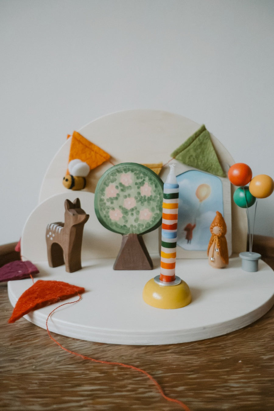 Halbrunder Jahreszeitentisch aus Holz zum Schrauben als Geburtstagstisch mit Lebenslicht, Luftballons und Filzwimpeln, Foto