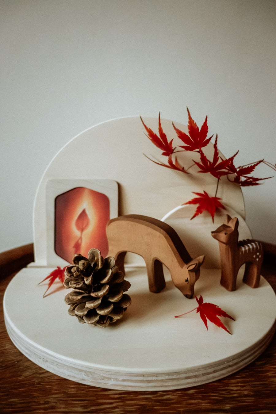 Halbrunder Jahreszeitentisch aus Holz zum Stecken als Herbsttisch mit Bilderrahmen, Rehen und Kiefernzapfen von der Seite, Foto