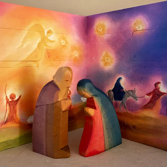 Adventskalender Baukje Exler, aufgestellter Kalender mit Maria, Josef und leuchtenden Sternen hinter Holzfiguren