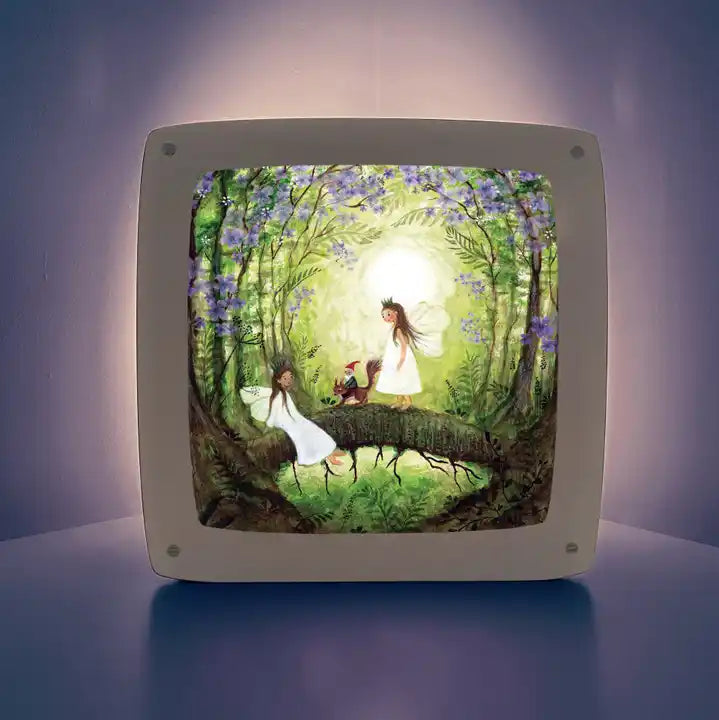 Motiv Feen mit Eichhörnchen von Bijdehansje für die magische Lampe: Zwei Feen mit Eichhörnchen auf einem Ast im grünen Wald unter lila Blüten