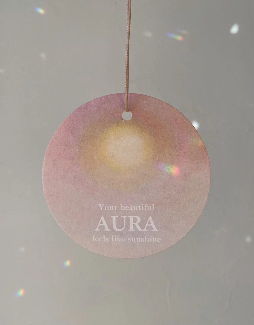 Geschenkanhänger „Your beautiful aura feels like sunshine“ von Anna Cosma, am Band vor hellem Hintergrund