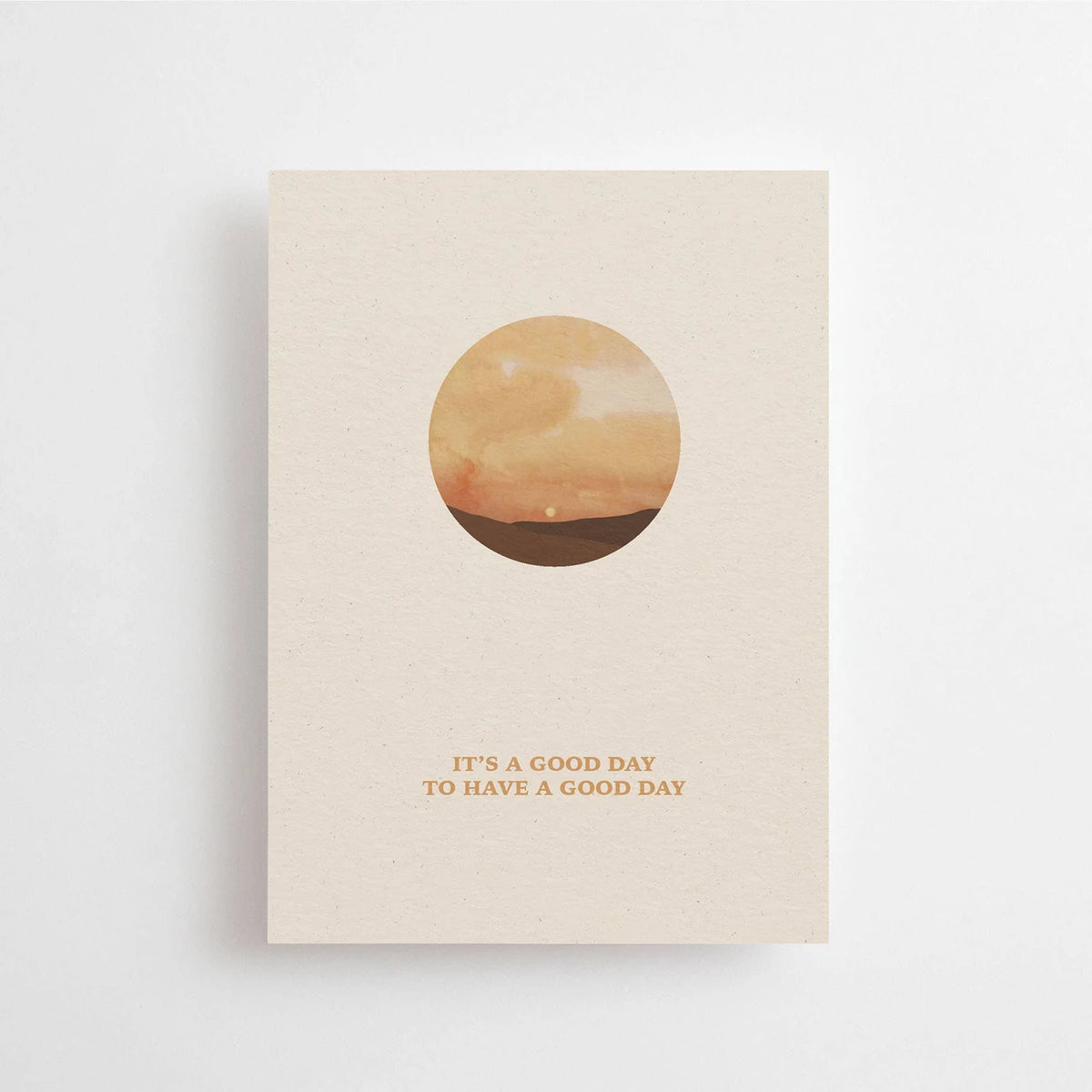 Postkarte A good day to have a good day von Anna Cosma A6: eine beige Karte mit einem Kreis, in dem ein Sonnenuntergang über dem Meer zu sehen ist, und dem Schriftzug „A good day to have a good day“