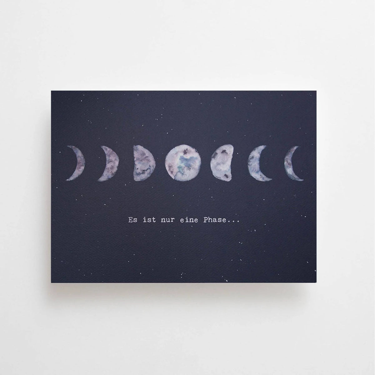 Postkarte Es ist nur eine Phase von Anna Cosma A6: eine dunkelblaue Karte im Querformat mit einer Reihe von Mondphasen und dem Schriftzug „Es ist nur eine Phase…“