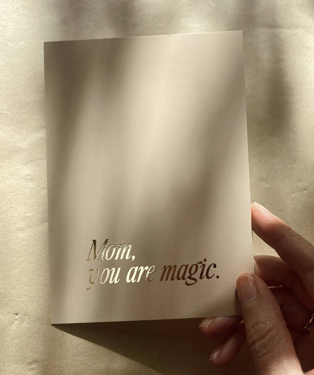 Postkarte „Mom, you are magic“ von Anna Cosma A6, in der Hand im Sonnenlicht
