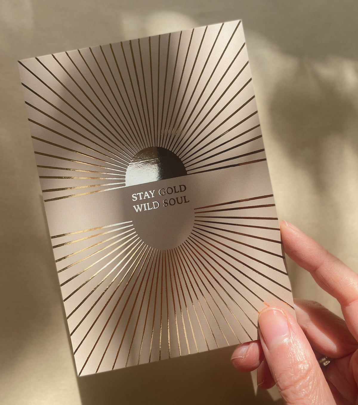 Postkarte „Stay gold wild soul“ von Anna Cosma A6, in der Hand im Sonnenlicht