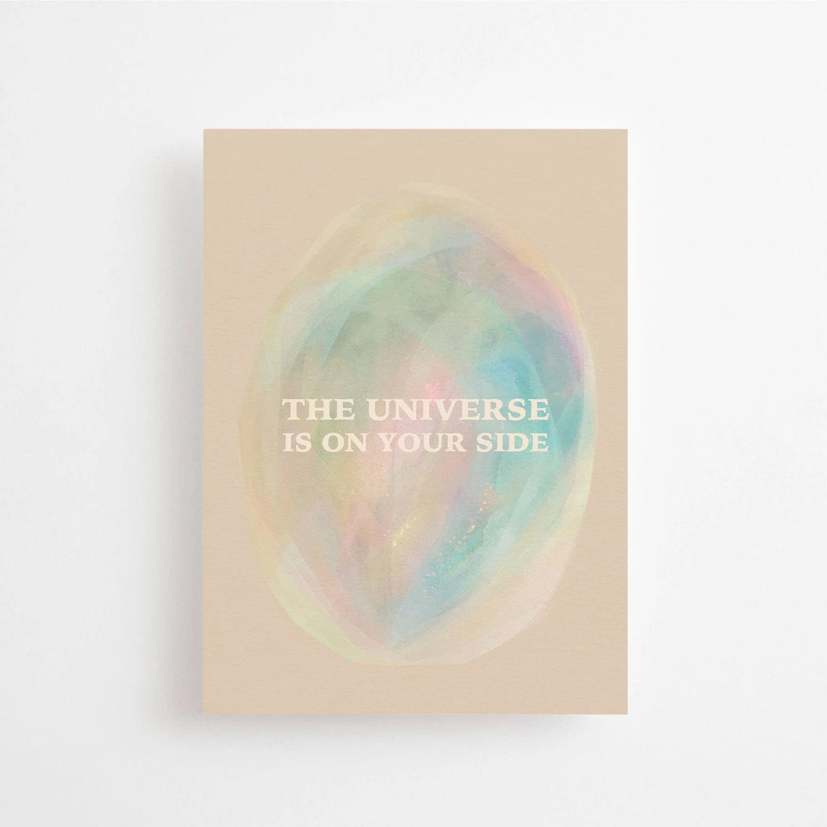 Postkarte The universe is on your side von Anna Cosma A6: eine beige Karte mit einem pastellfarbenen, schimmernden Oval wie ein Nebel im All und dem Schriftzug „The universe is on your side“