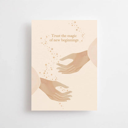 Postkarte Trust the magic of new beginnings von Anna Cosma A6: eine Karte in Pfirsich und Rosé mit zwei Händen, zwischen denen kleine Funken schweben, und dem Schriftzug „Trust the magic of new beginnings“