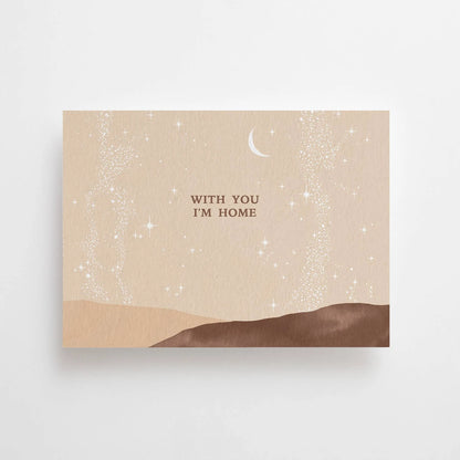 Postkarte With you I'm home von Anna Cosma A6: eine beige Karte im Querformat mit sanften Hügeln in Braun und dem Schriftzug „With you I’m home“