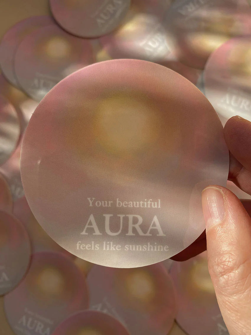 Vinyl-Sticker „Your beautiful aura feels like sunshine“ von Anna Cosma, in der Hand auf weiteren Stickern