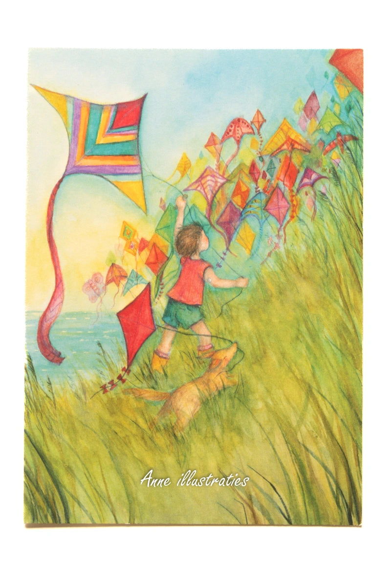 Postkarte Drachensteigen von Anne Gies A6: ein Kind in rotem Hemd rennt mit einem Hund durch hohes Gras und lässt eine lange Kette bunter Drachen steigen