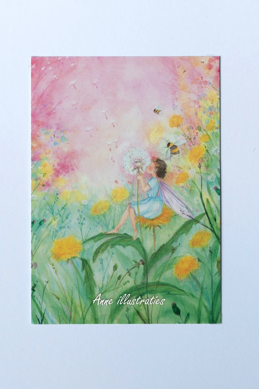 Postkarte Löwenzahn-Elfe von Anne Gies A6: eine kleine Elfe im blauen Kleid sitzt auf einer Löwenzahnblüte und pustet die Samen in den rosa Himmel, ringsum Bienen