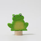 Grimm's Steckfigur Frosch, der grüne Frosch sitzt breit lächelnd auf seinem Holzfuß