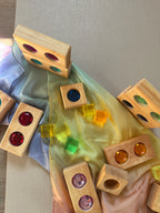 Bauspiel Märchenfenster natur aus Erlenholz mit bunten, durchscheinenden Funkelsteinen, zusammen mit Lichtbauwürfeln auf einem Spieltuch, Foto