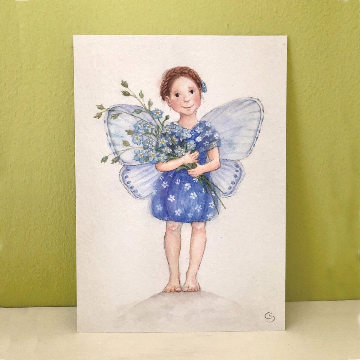 Postkarte Elfe Vergissmeinnicht von Corinna Schwerdtfeger A6 an eine Wand gelehnt, Stimmungsbild