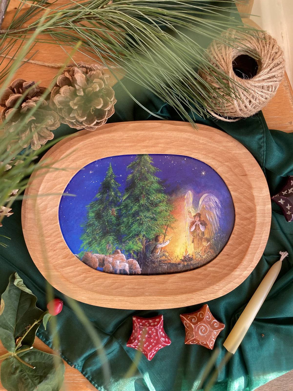 Postkarte Hirtenfeuer von Daniela Drescher A6 im ovalen Bilderrahmen aus Holz, auf grünem Tuch mit Tannenzweigen und Bienenwachskerze
