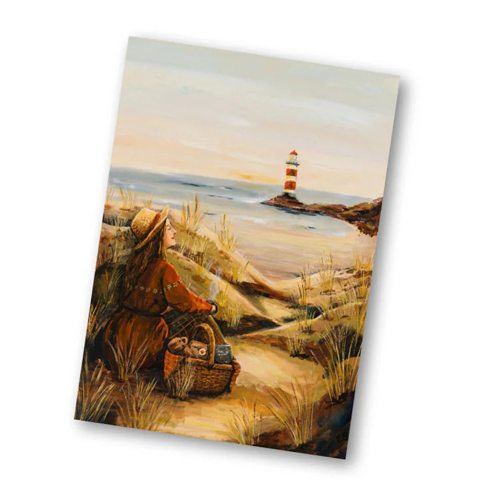 Postkarte An der Küste von Esther Bennink A6: eine Küste mit Dünen und Leuchtturm, im Vordergrund ein Picknickkorb und ein Hut