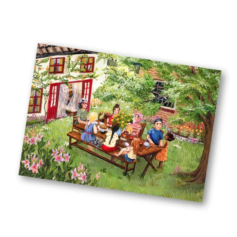 Postkarte Sommertage von Esther Bennink A6: eine Familie sitzt an einem langen Tisch im Garten vor einem roten Haus