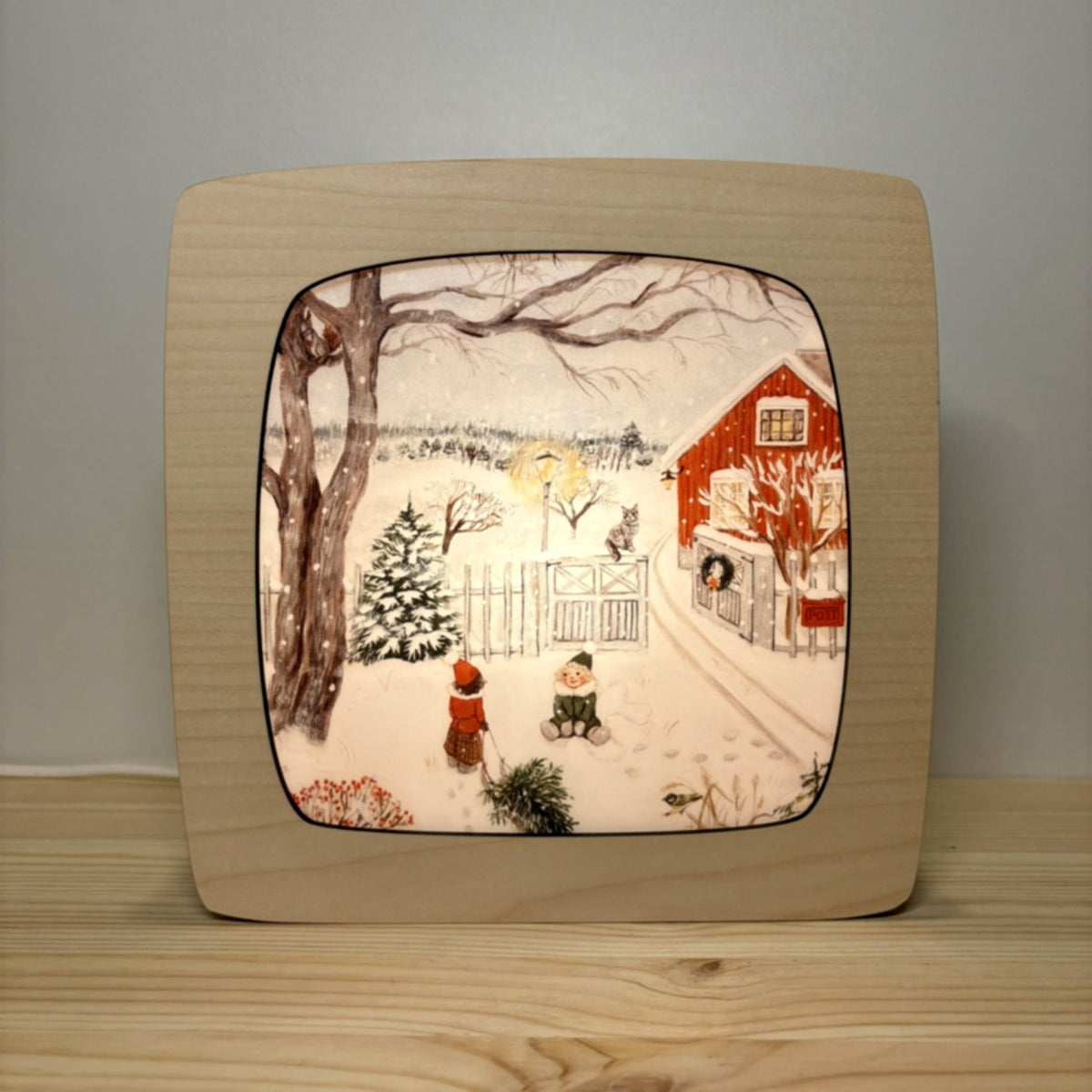 Motiv Dezembergeschichten von Goose Grass Illustrations in der magischen Lampe, zwei Kinder im Schnee vor einem roten Haus mit Kranz und einer kleinen Tanne