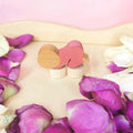 Stecker Schlafendes Baby pink von Hamer & Zaag, schlafendes Baby unter rosa Decke auf Rosenblättern
