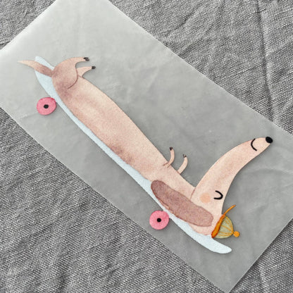 Bügelbild - Dackel auf Skateboard liegend