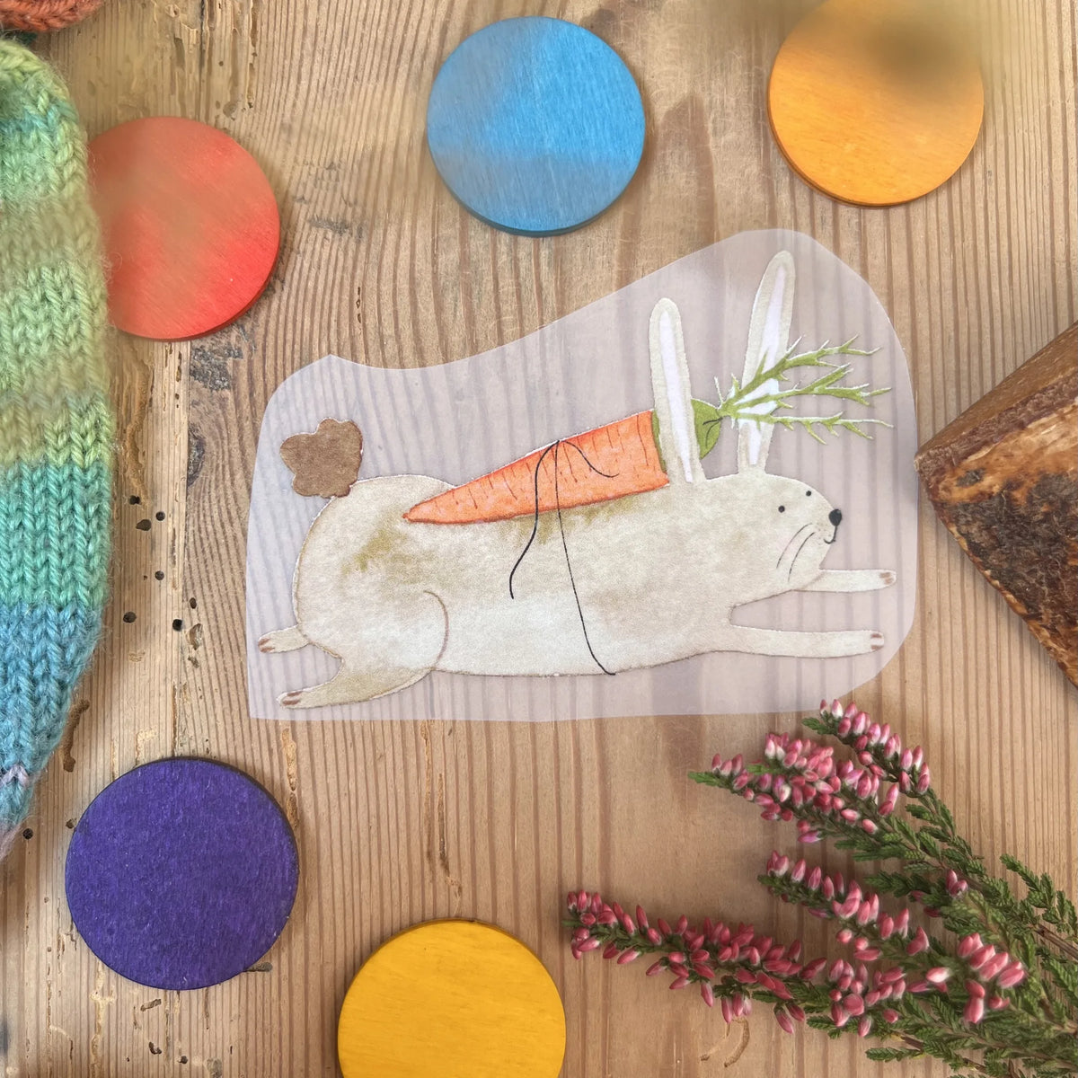 Hannahs Firlefanz Bügelbild laufender Hase mit Möhren-Schultüte, auf Holz zwischen bunten Holzscheiben