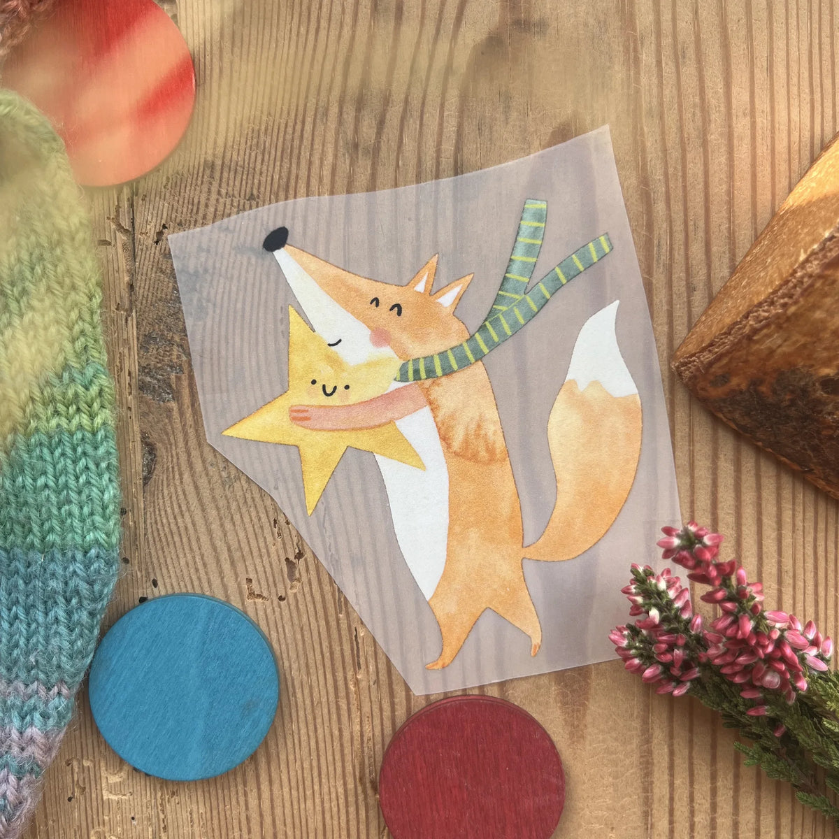 Hannahs Firlefanz Bügelbild Fuchs, der einen gelben Stern umarmt, auf Holz zwischen bunten Holzscheiben