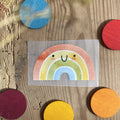 Hannahs Firlefanz Bügelbild lachender Regenbogen, auf Holz zwischen bunten Holzscheiben