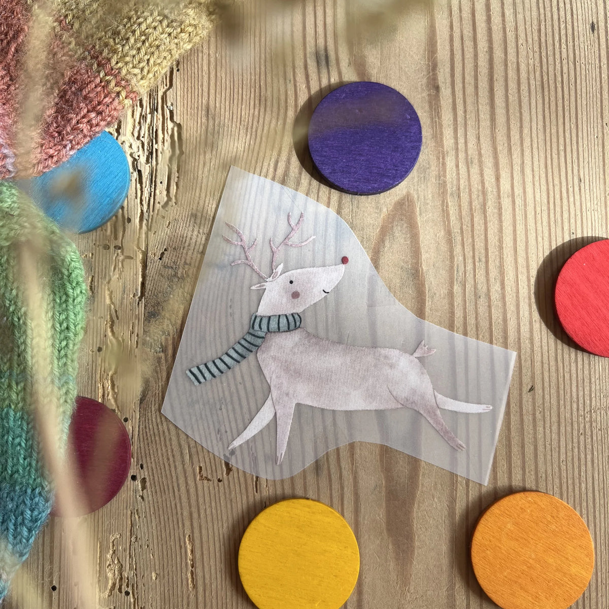 Hannahs Firlefanz Bügelbild laufendes Rentier mit Schal, auf Holz zwischen bunten Holzscheiben
