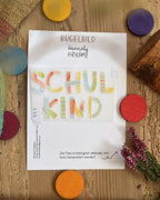 Hannahs Firlefanz Bügelbild Schriftzug Schulkind in bunten Buchstaben, auf der Bügelbild-Karte in der Tüte