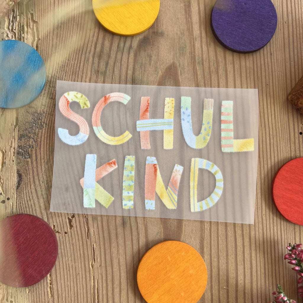 Hannahs Firlefanz Bügelbild Schriftzug Schulkind in bunten Buchstaben, auf Holz zwischen bunten Holzscheiben