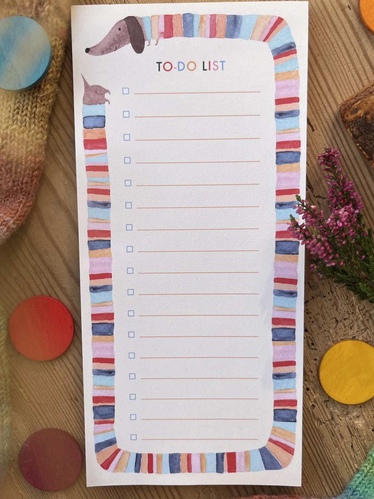 Hannahs Firlefanz Notizblock To-do-Liste mit langem Dackel im Ringelpulli als Rahmen, auf Holz zwischen bunten Holzscheiben und Heide