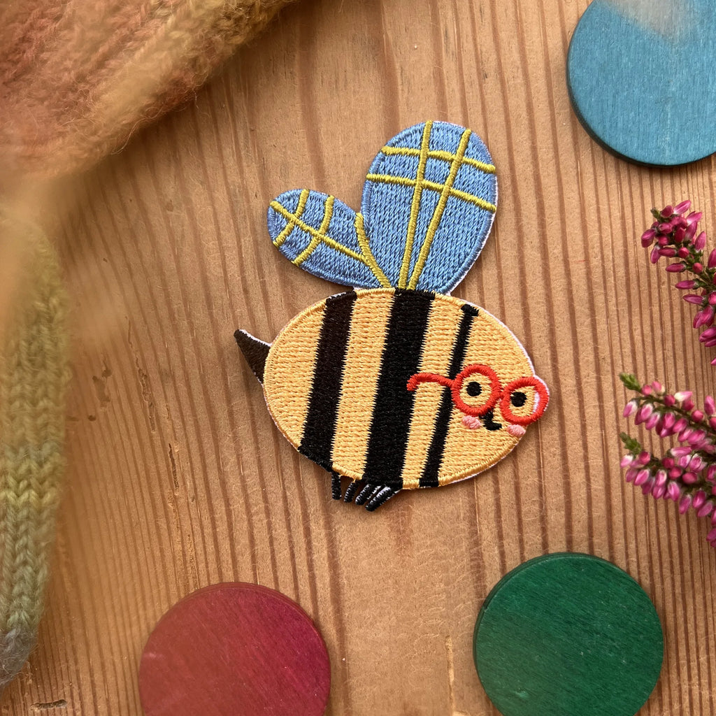 Hannahs Firlefanz Patch Biene mit roter Brille, gestickt, auf Holz zwischen bunten Holzscheiben