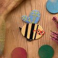 Hannahs Firlefanz Patch Biene mit roter Brille, gestickt, auf Holz zwischen bunten Holzscheiben