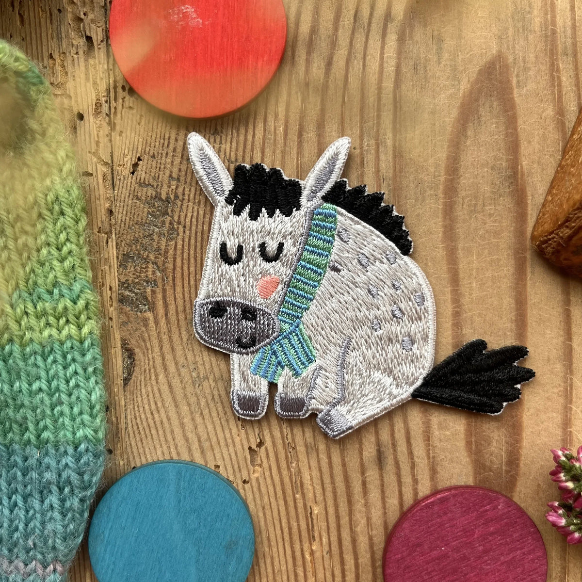 Hannahs Firlefanz Patch schlafender Esel mit Schal, gestickt, auf Holz zwischen bunten Holzscheiben