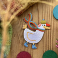 Hannahs Firlefanz Patch Gans mit Regenbogenschal und Mütze, gestickt, auf Holz zwischen bunten Holzscheiben