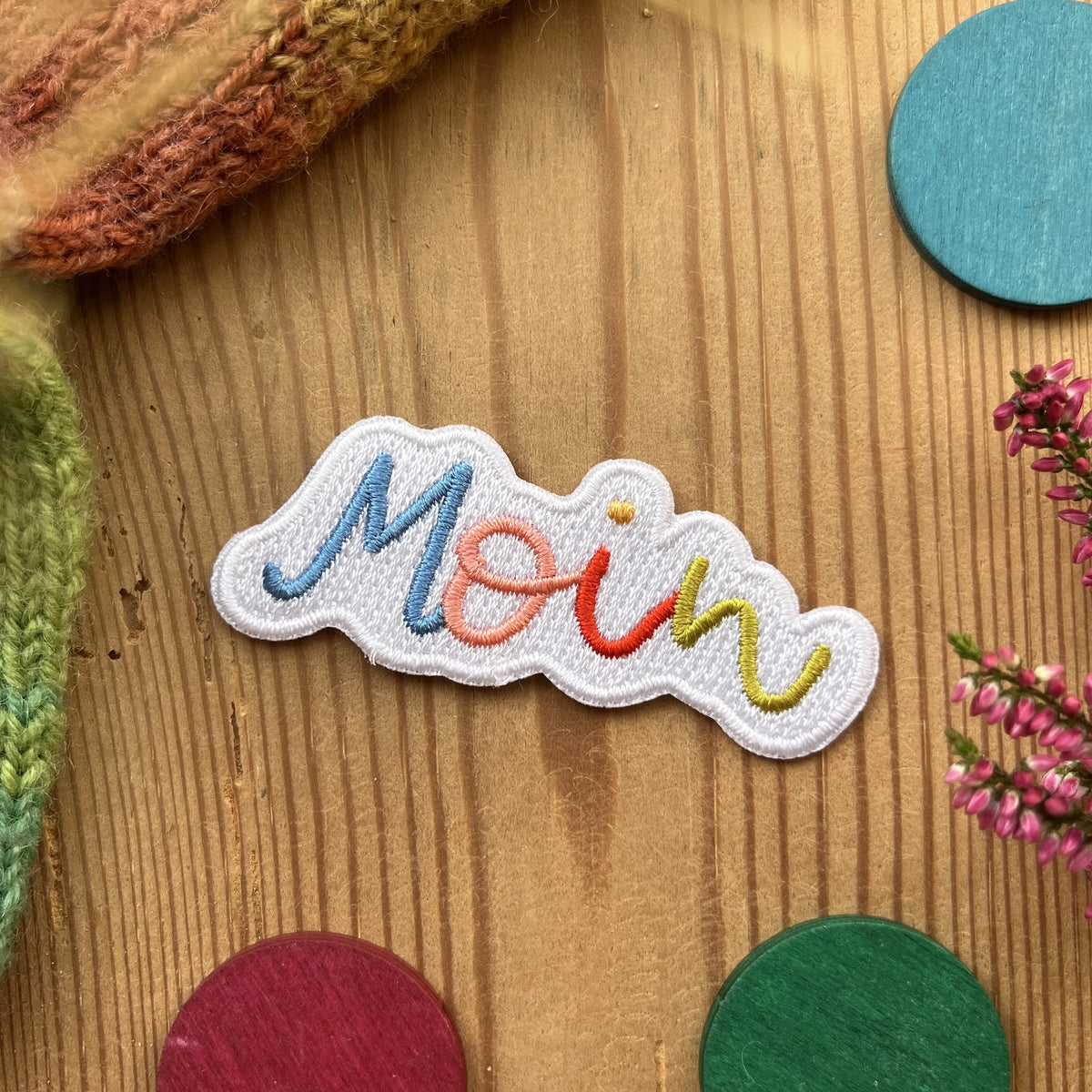 Hannahs Firlefanz Patch Schriftzug Moin in Regenbogenfarben, gestickt, auf Holz zwischen bunten Holzscheiben