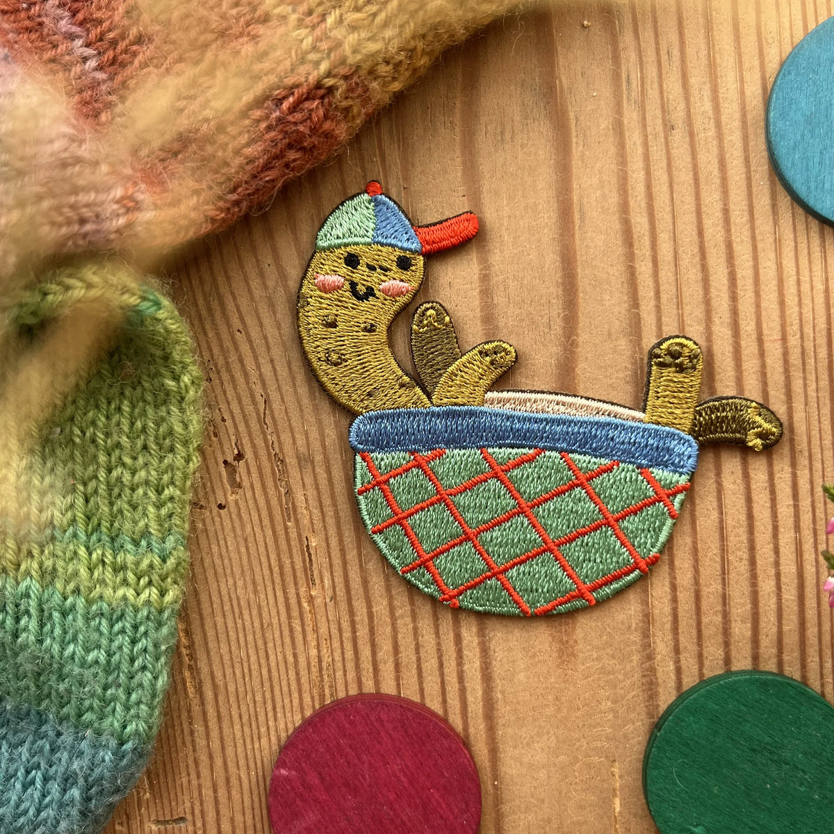 Hannahs Firlefanz Patch Schildkröte mit Cap in einer Schale, gestickt, auf Holz zwischen bunten Holzscheiben