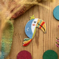 Hannahs Firlefanz Patch Tukan mit Regenbogenschnabel, gestickt, auf Holz zwischen bunten Holzscheiben