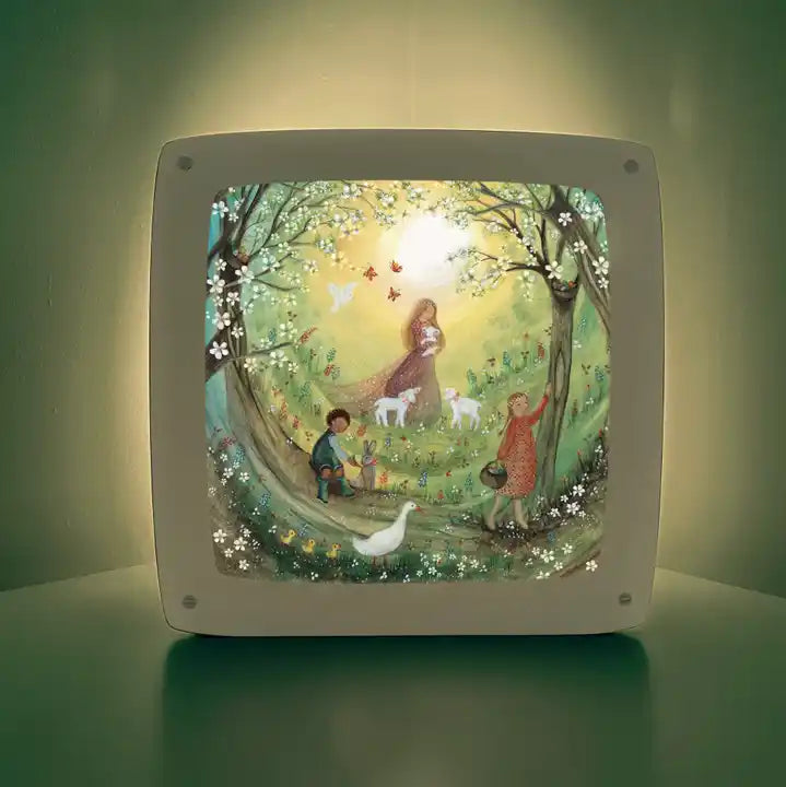 Motiv Frohe Ostern von Bijdehansje für die magische Lampe: Kinder mit Lämmern und einer Gans im blühenden Frühlingswald