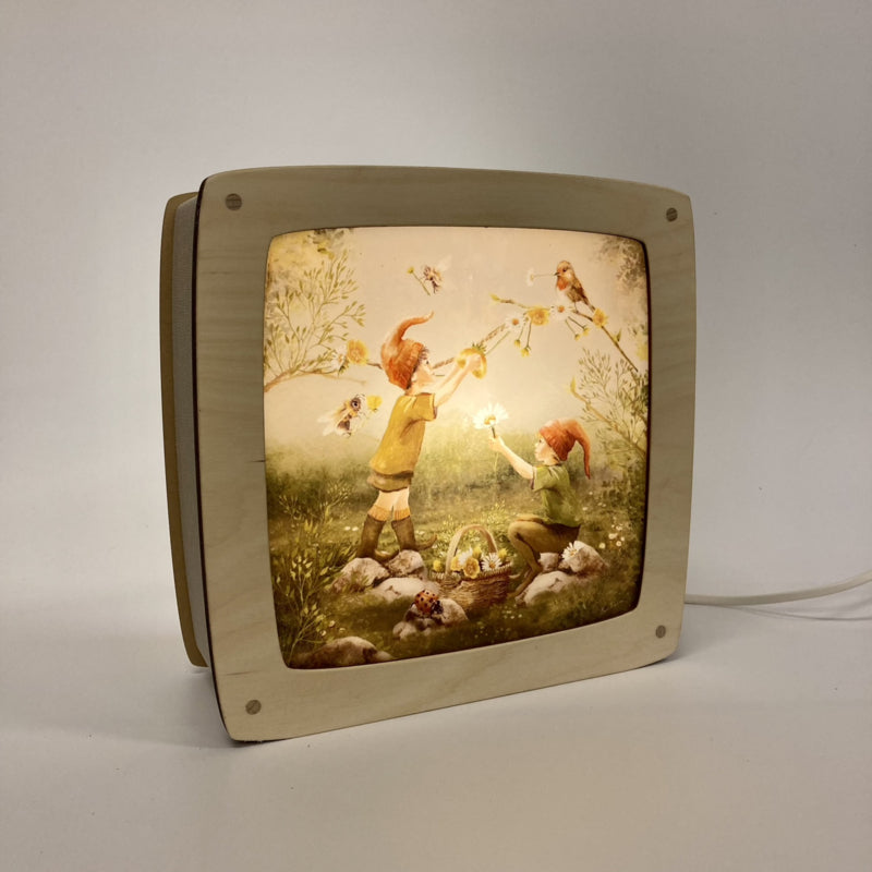 Motiv Vögel und Bienen von Iris Esther in der magischen Lampe, zwei Wichtelkinder mit roten Mützen auf einer Blumenwiese mit Vögeln und Bienen