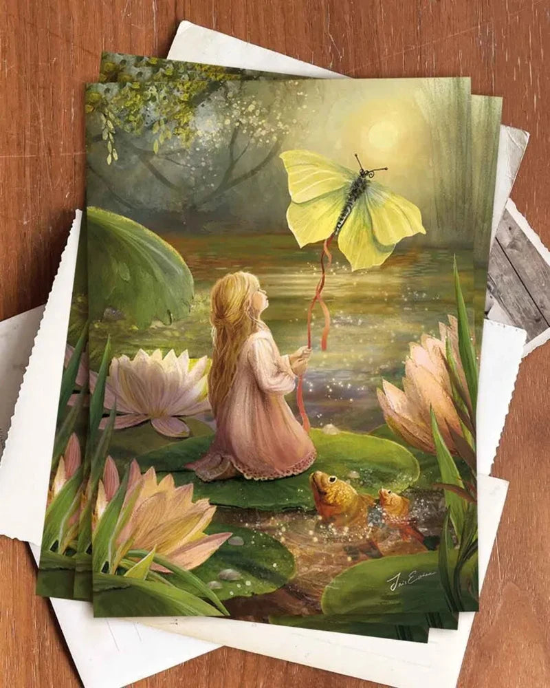 Postkarte Däumelinchen von Iris Esther A6, mehrere Karten auf einem Holztisch
