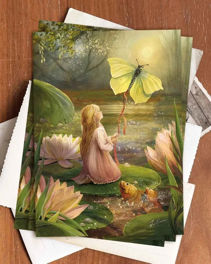 Postkarte Däumelinchen von Iris Esther A6, mehrere Karten auf einem Holztisch